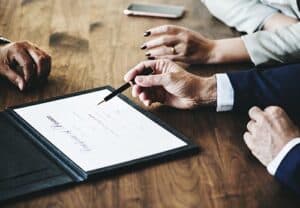 Hands signing divorce papers on a wooden table, representing the legal process of divorce in Texas.