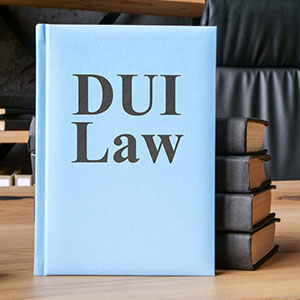 A light blue book titled "DUI Law" sits on a desk next to a stack of other books.