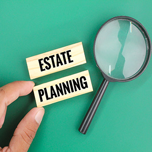 Estate planning concept with wooden blocks, magnifying glass, and hand on green background